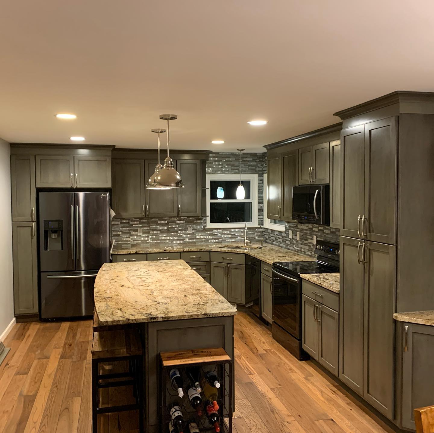 Modern kitchen: gray cabinets, steel appliances. Island with granite top and wine rack.